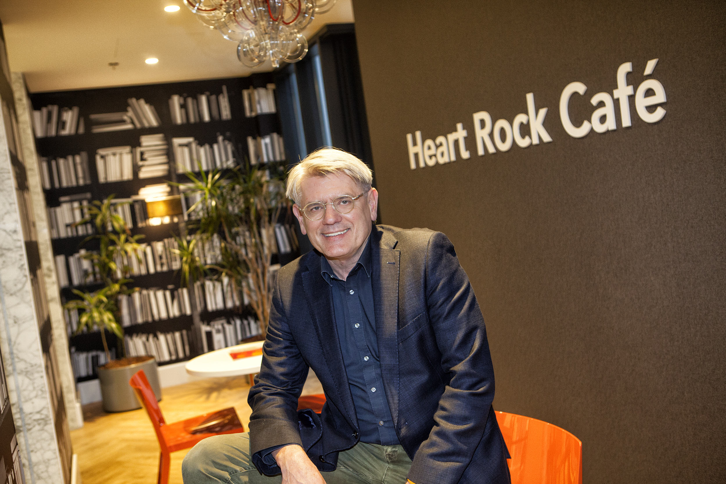 Man, zittend op tafel voor grote boekenkast in het Heart Rock Café